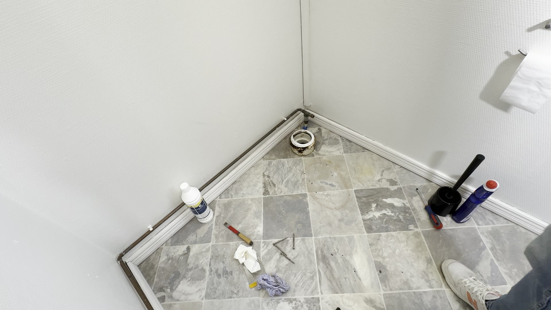 Gulv med afløb og værktøj efter det gamle toilet er fjernet